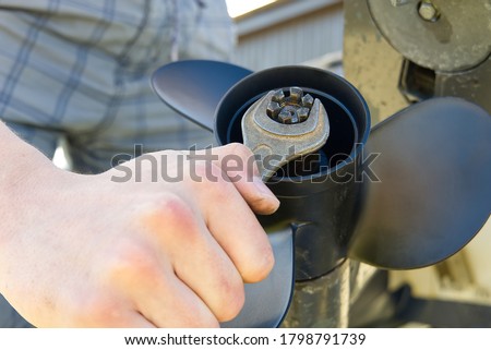 man changing propeller on outboard motor. Repairing outboard motor for boat, replacing screw. Royalty-Free Stock Photo #1798791739