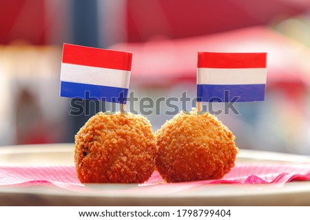 Bitterballen, Two balls of Dutch meat-based snack in wooden plate and small Netherlands flags on top, Typically containing a mixture of beef or veal, Bitterballen are one of Holland's favorite snacks. Royalty-Free Stock Photo #1798799404