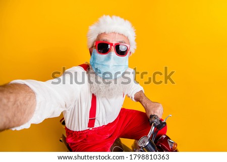 Self-portrait of his he nice funny funky elderly guy wearing Santa costume wearing safety gauze mask riding moped delivering gifts stay home isolated bright vivid shine vibrant yellow color background