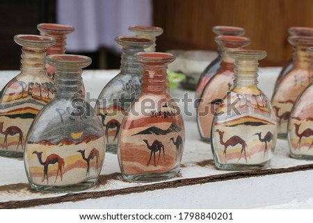 Group of sand bottles with different pictures of camels in desert. Traditional souvenir from Middle East county. Theme of shopping during travel.