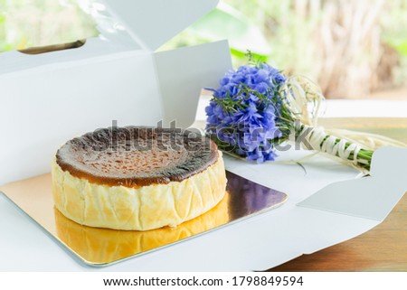 Basque burnt cheesecake with with hydrange bouquet on wooden table.