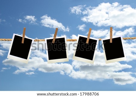 instant photos hanging on a rope with clothespins against blue sky
