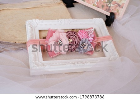 Beautiful handmade flowers made out of fabric cloth in pastel pink theme color placed on white photo frame that can be used as hair accessory, decoration, and embellishment