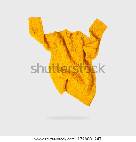 Yellow orange flying women's autumn knitted sweater on light gray background. Creative clothing concept, trendy fall winter cozy sweater pullover jersey. Women's fashion, autumn discounts. Shopping Royalty-Free Stock Photo #1798881247