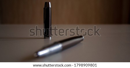 Cap and beautiful dark pen on grey office table. Concept.