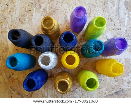 Glass bottles are decorated in bright colors. Yellow, white, black, purple, turquoise, gold, green cans on the wooden surface.