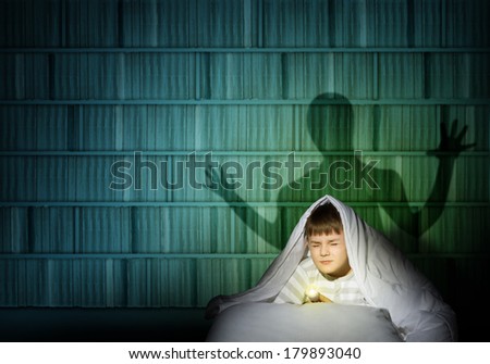 image of a boy under the covers with a flashlight the night afraid of ghosts