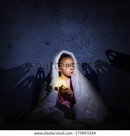 image of a girl under the covers with a flashlight the night afraid of ghosts