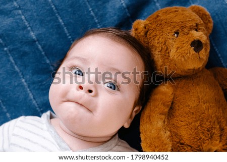 Smiling baby with toy on blue background top view