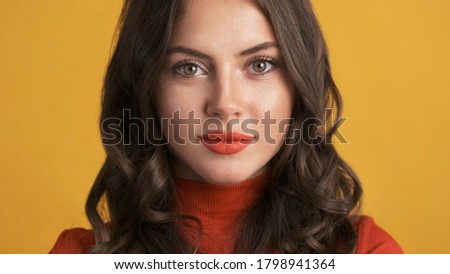 Portrait of gorgeous brunette girl with red lips intently looking in camera over colorful background  