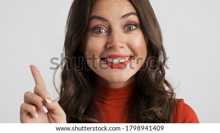 Portrait of beautiful excited brunette girl having new idea happily looking in camera over white background