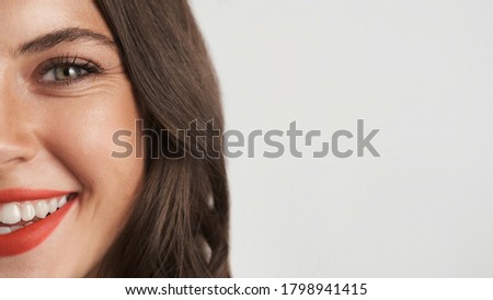 Close up half face of beautiful smiling brunette girl with red lips happily looking in camera isolated. Copy space 
