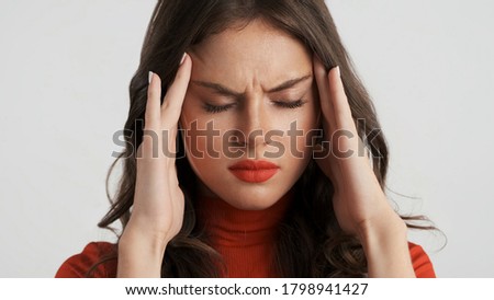 Portrait of upset brunette girl showing headache on camera over white background