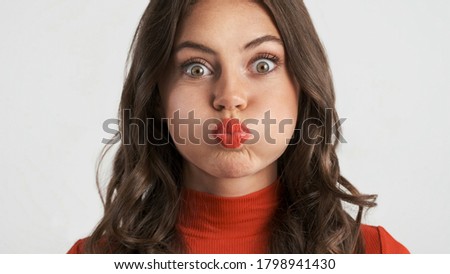 Portrait of pretty funny brunette girl fooling around on camera over white background