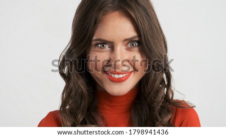 Portrait of attractive brunette girl weirdly looking in camera and smiling over white background