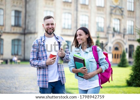 Two young best friends from university in casual clothes with backpack have a conversation on campus background and laughing