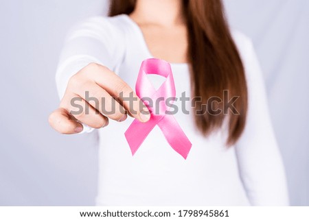 Breast cancer awareness ribbon on woman chest on grey background. Medical, healthcare for advertising concept.