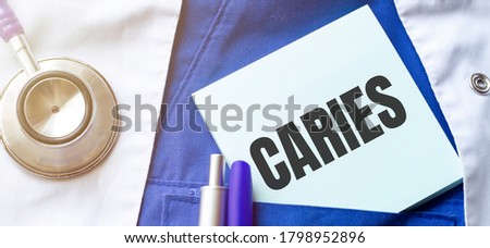 stethoscope, pens and note with text caries on the doctor uniform
