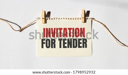 INVITATION FOR TENDER text words inscription on yellow sticker note on white wall or table.