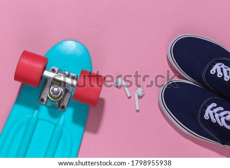 Cruiser board and wireless headphones, sneakers on a bright pink background. Youth accessories, hipster outfit. Top view. Flat lay