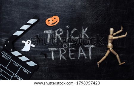 Movie Clapperboard and Chalk lettering Trick or treat on a chalk board with helloween decor. Halloween theme