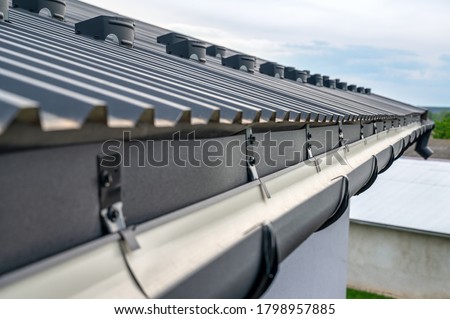. Gutter system for a metal roof. Holder gutter drainage system on the roof. Royalty-Free Stock Photo #1798957885