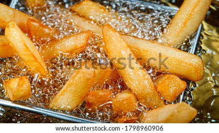 Cooking french fries in the deep fryer, crispy fries, Junk food concept Royalty-Free Stock Photo #1798960906