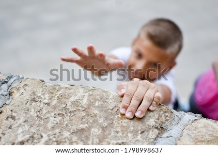 boy overcoming efforts. striving for a goal. conquering the top of the mountain. achieve a difficult goal. boy hanging on the wall. Royalty-Free Stock Photo #1798998637