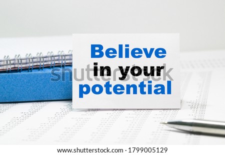 BELIEVE IN YOUR POTENTIAL text on white card, amid financial statements