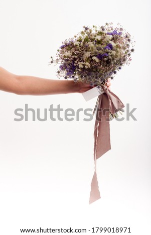 Studio shot female hand holding bouquet of wildflowers, minimalistic bouquet, greeting card