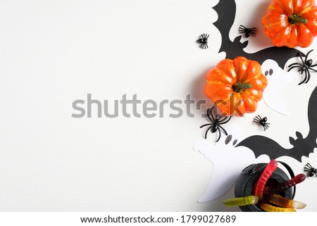 Halloween flat lay composition with pumpkins, buts, treats, spiders on white desk. Halloween background. Halloween party invitation card, banner mockup. Top view.
