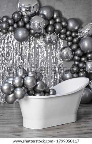 black and white photo white stylish bathtub in empty room with balloons and confetti.