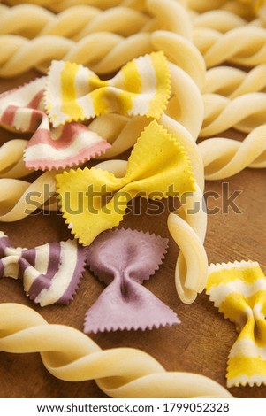 dry multicolored Italian handmade macaroni (pasta), close-up on a log cabin and a wooden table. 