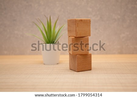 Three wooden toy cubes arranged in vertical on white grey wooden background.
