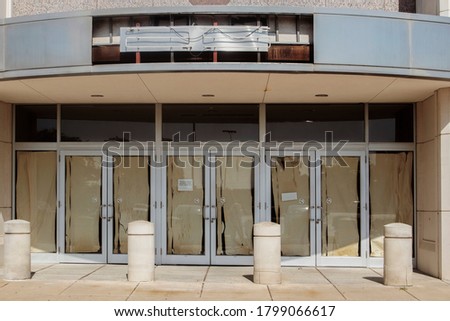 Abandoned store at mall with ripped paper over doors and ripped out neon sign