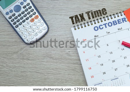 Word on tax time, calendar and calculator on wooden table 