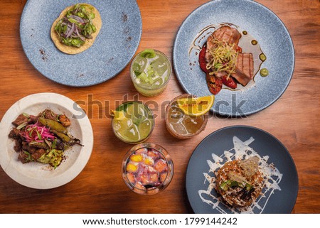 Dinner table with different dishes and alcoholic cocktails on wooden table. Restaurant concept. Gourmet table setting.