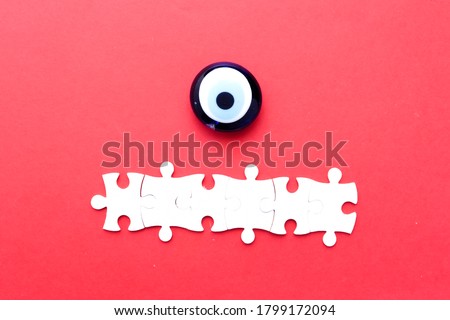Turkish evil eye and copyspace jigsaw puzzle on red background.