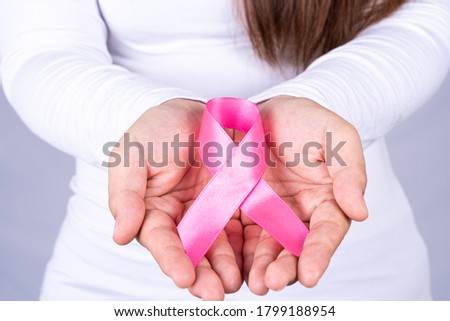 Woman hands holding pink breast cancer awareness ribbon. Medical, healthcare for advertising concept.