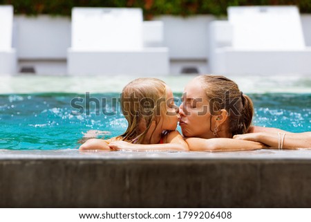 Happy people at pool side. Funny photo of young mother with child relaxing in outdoor swimming pool. Family lifestyle, kids with parents on summer holiday.
