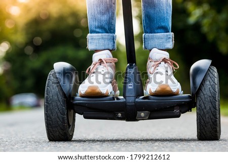 A young hipster girl driving a hoverboard outdoors in a Park, an active woman balancing on a modern electric Board, the concept of the future, alternative transport, ecology and the environment.