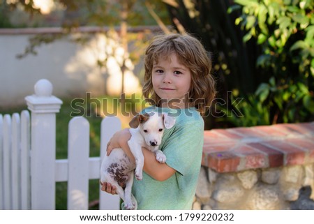 Kid with puppies kissing and hugging. Lovely child with dog walking outdoor