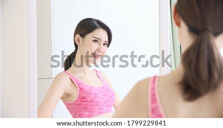 asian sport woman look her body in front of mirror