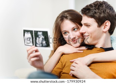 Beautiful couple watching with emotion sonography pictures of their baby