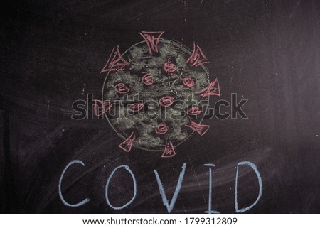 Chalk drawing of a virus COVID-19 on the background of the blackboard. Back to school