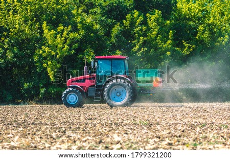 The tractor applies fertilizer to the soil. Agricultural work. Royalty-Free Stock Photo #1799321200