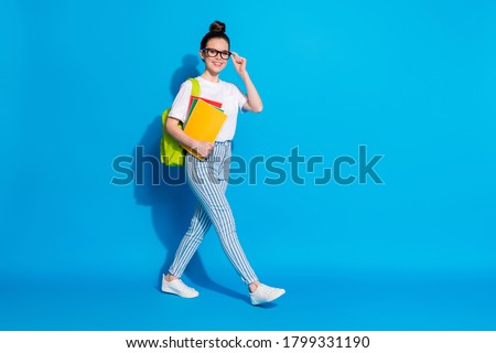 Full body profile side photo of positive college student girl go copyspace hurry scholar lectures hold copybooks bag wear white stylish trendy clothes isolated bright shine color background