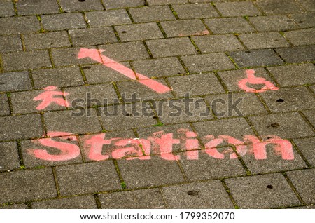 The word "station", an arrow and a symbol for pedestrians and wheelchairs, witten in red paint on the pavement to indicate a temporary route to Zwolle railway station in The Netherlands