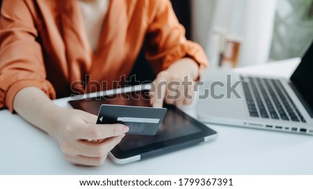 Business people use tablets and hold credit cards as an online shopping concept With a calculator and a book placed on the table