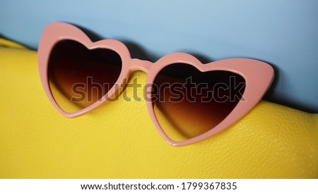 Yellow bag and heart-shaped sunglasses on blue background - summer picture